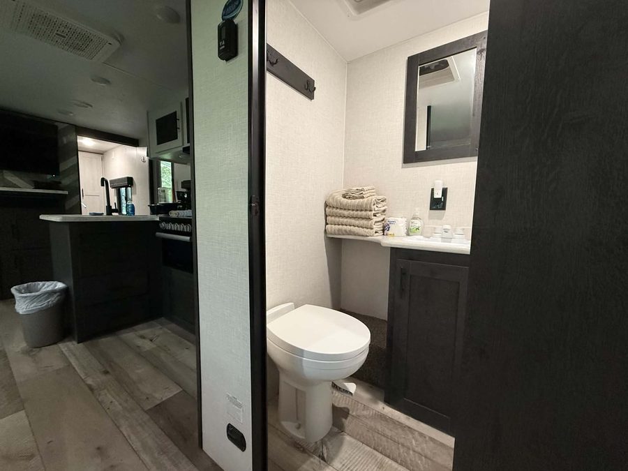 Bathroom with toilet and vanity, looking back toward the kitchen, in the bunkhouse RV rental